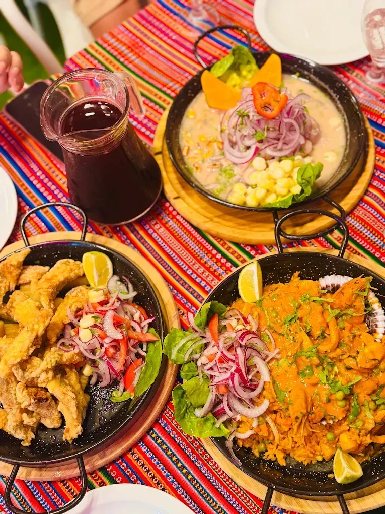 Plato de pollo y arroz servido en sartén negra, adornado con verduras y encurtidos.
