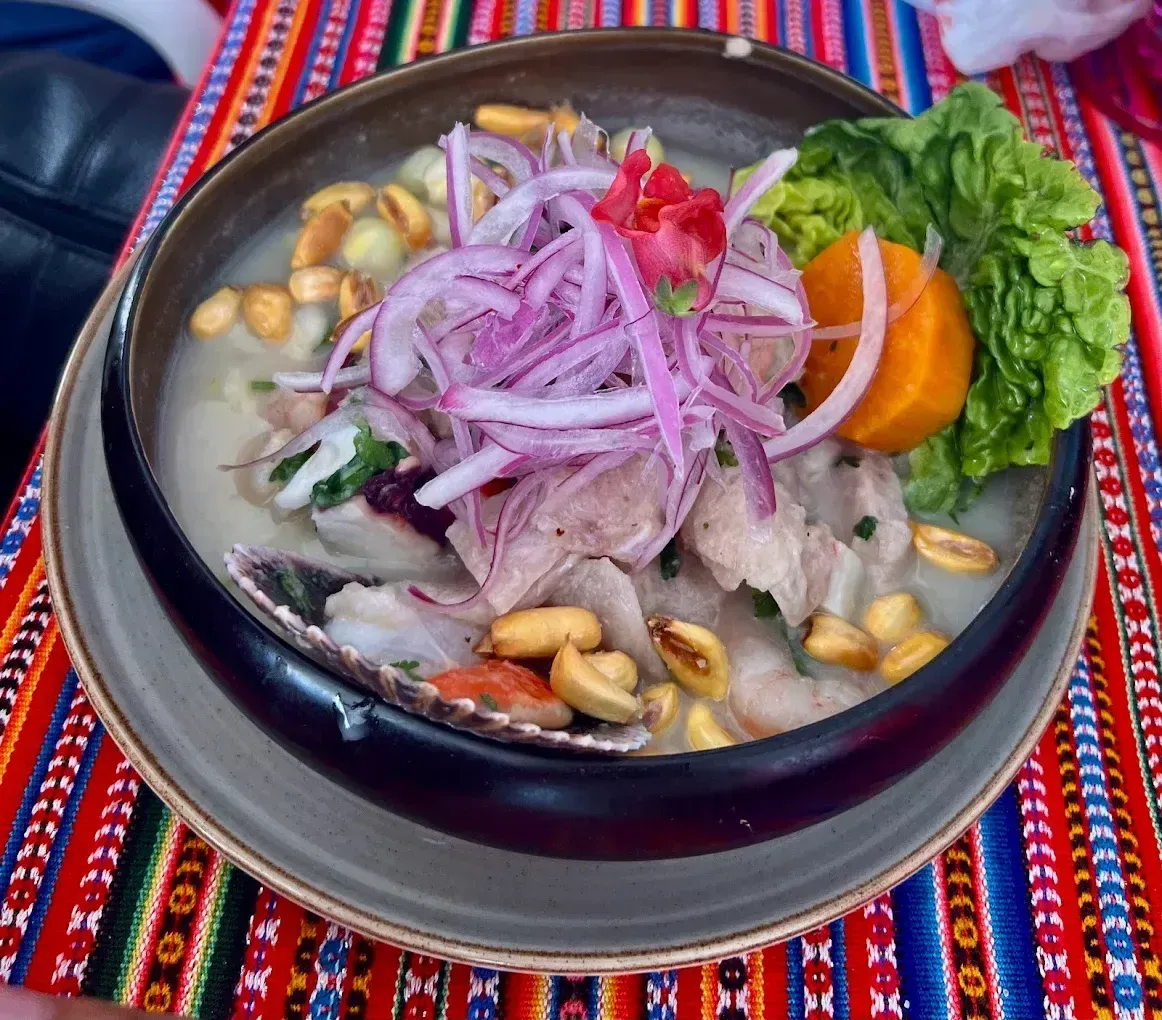 Ceviche peruano en plato con cebolla morada, maní y camote.