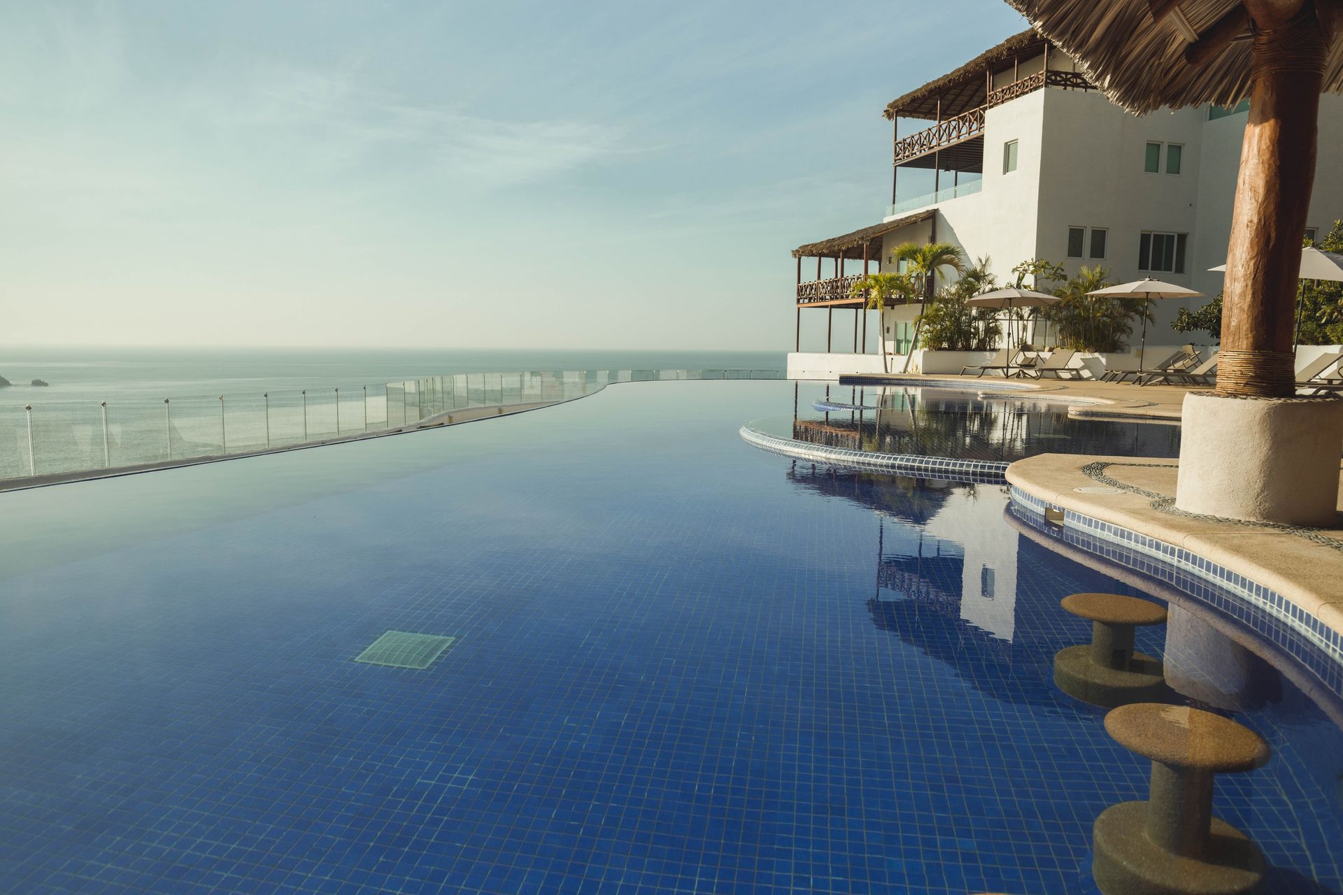 A large swimming pool with a view of the ocean and a building in the background.