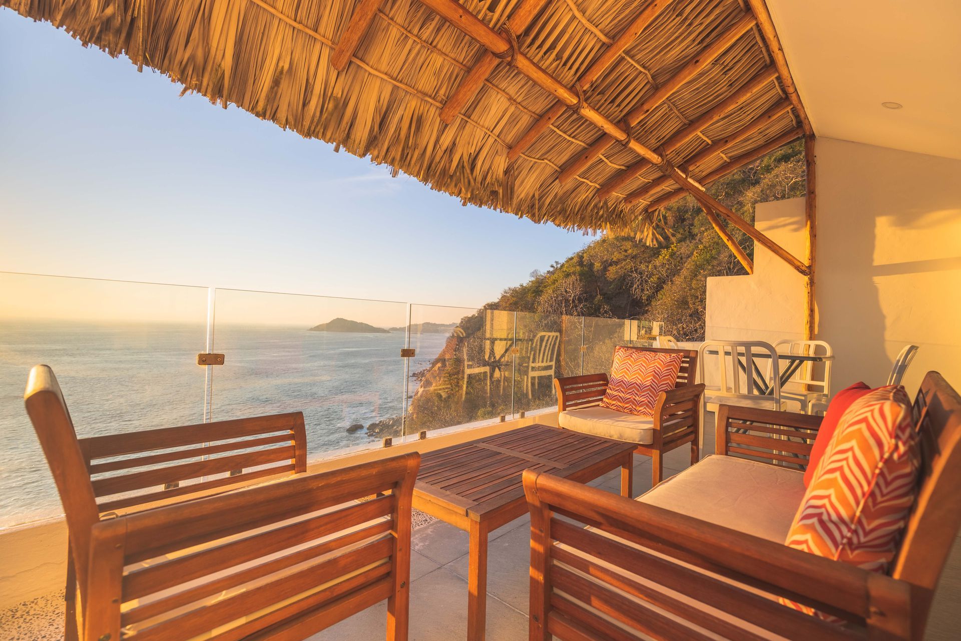A balcony with chairs and a table overlooking the ocean
