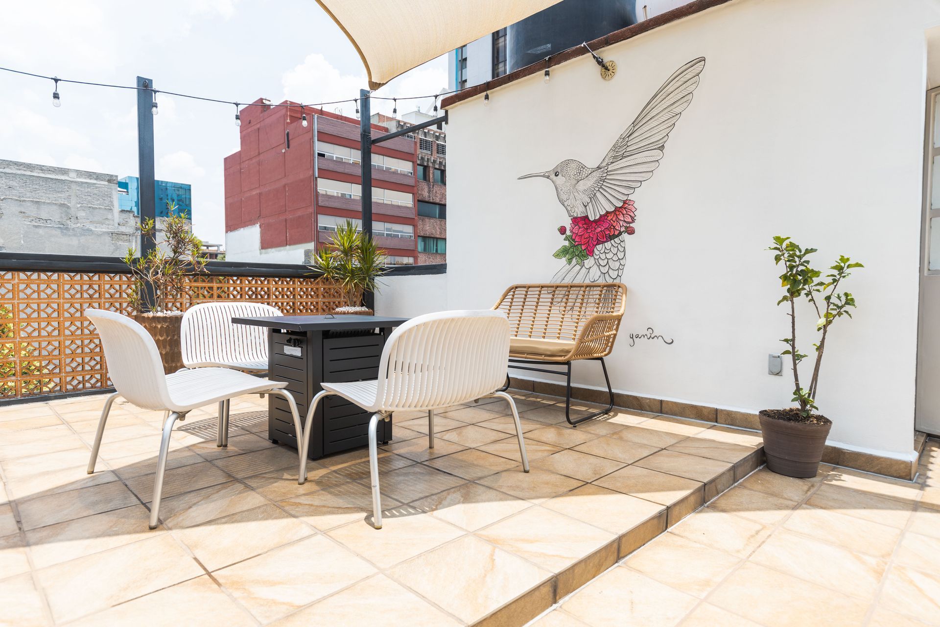 A patio with a table and chairs and a hummingbird painting on the wall.