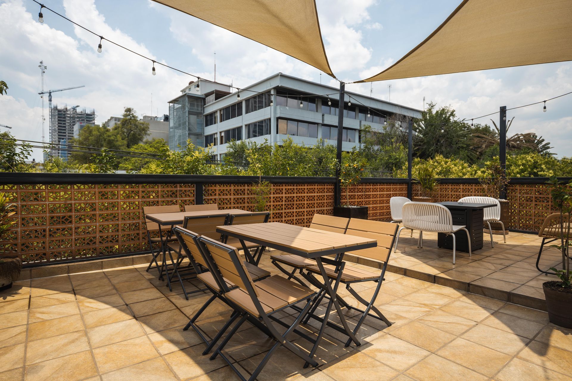 A patio with tables and chairs under umbrellas with a building in the background.