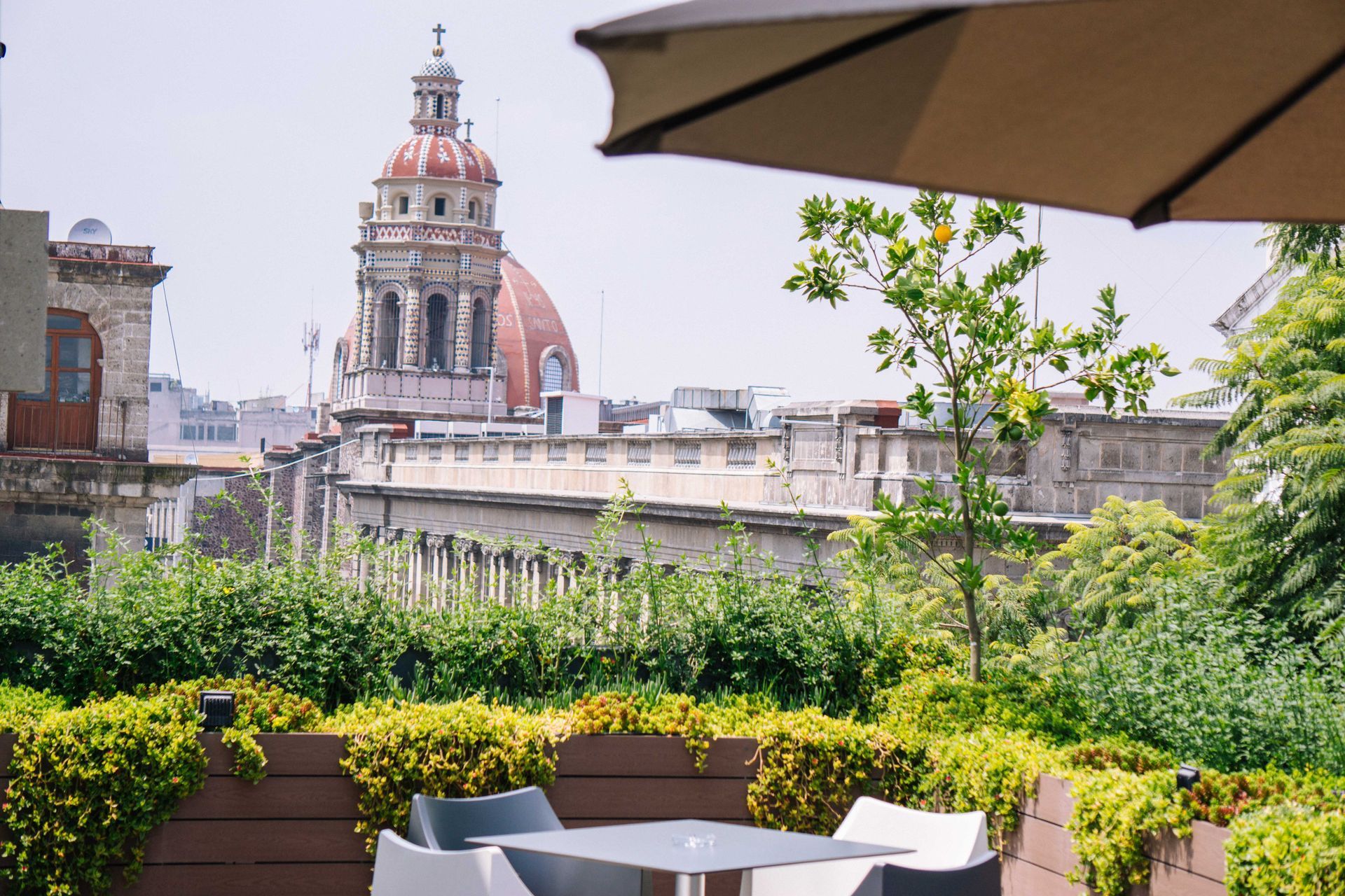 A table and chairs on a rooftop with a view of a city.