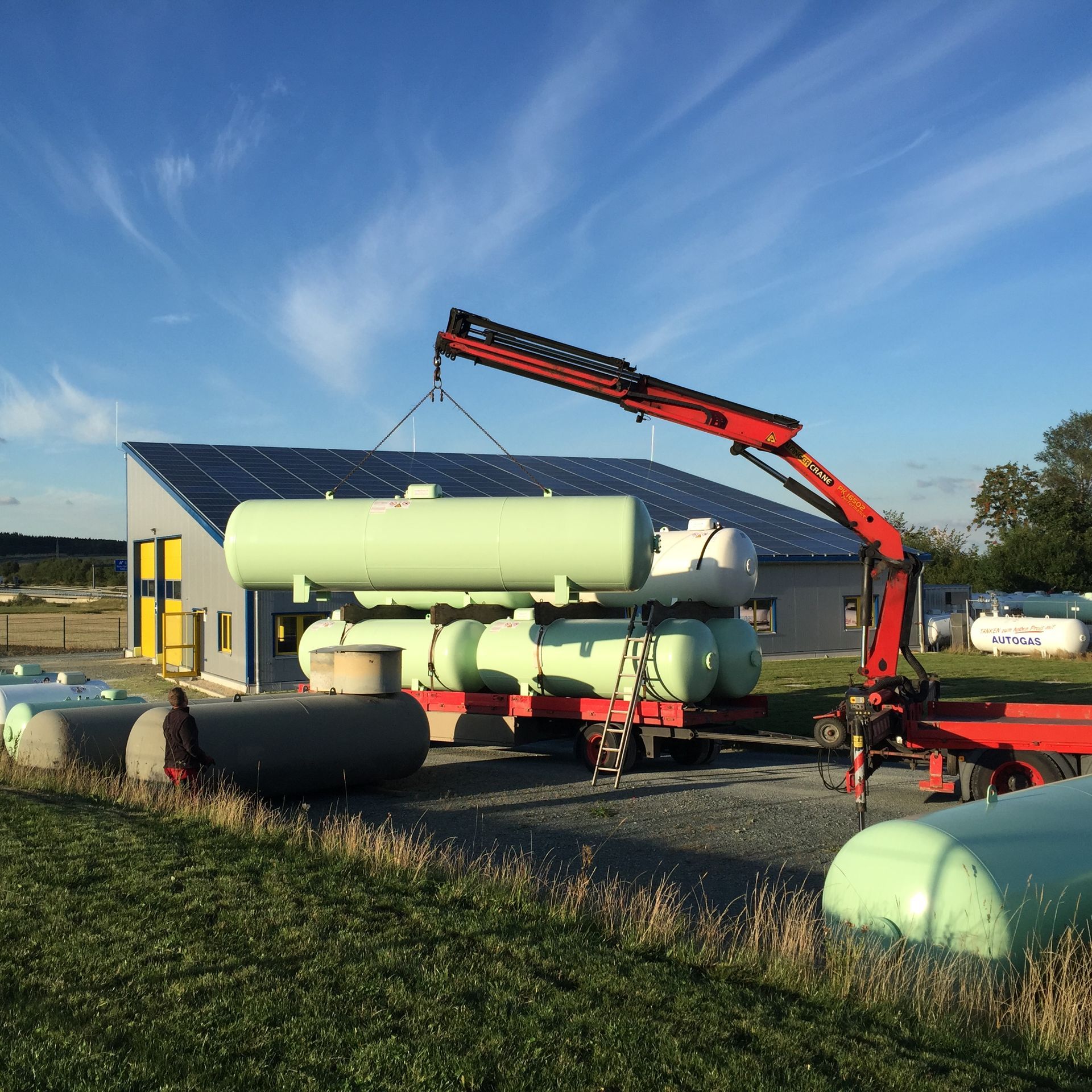 Eine Person stapelt im Freien blaue Propangasflaschen.