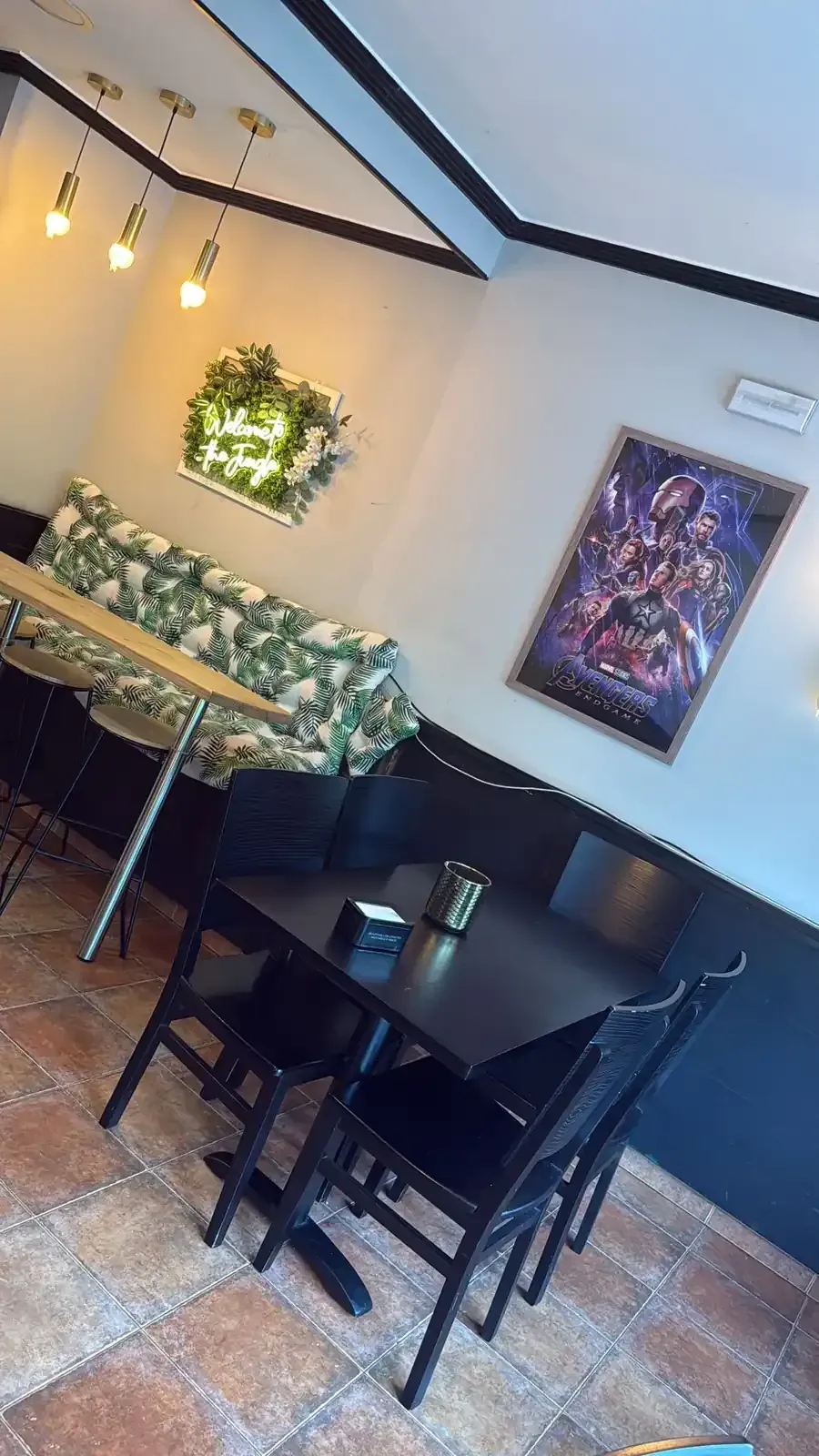 Fotografía interior de un espacio comercial con un mostrador de recepción de ladrillo, piso de baldosas y paredes verdes y negras.