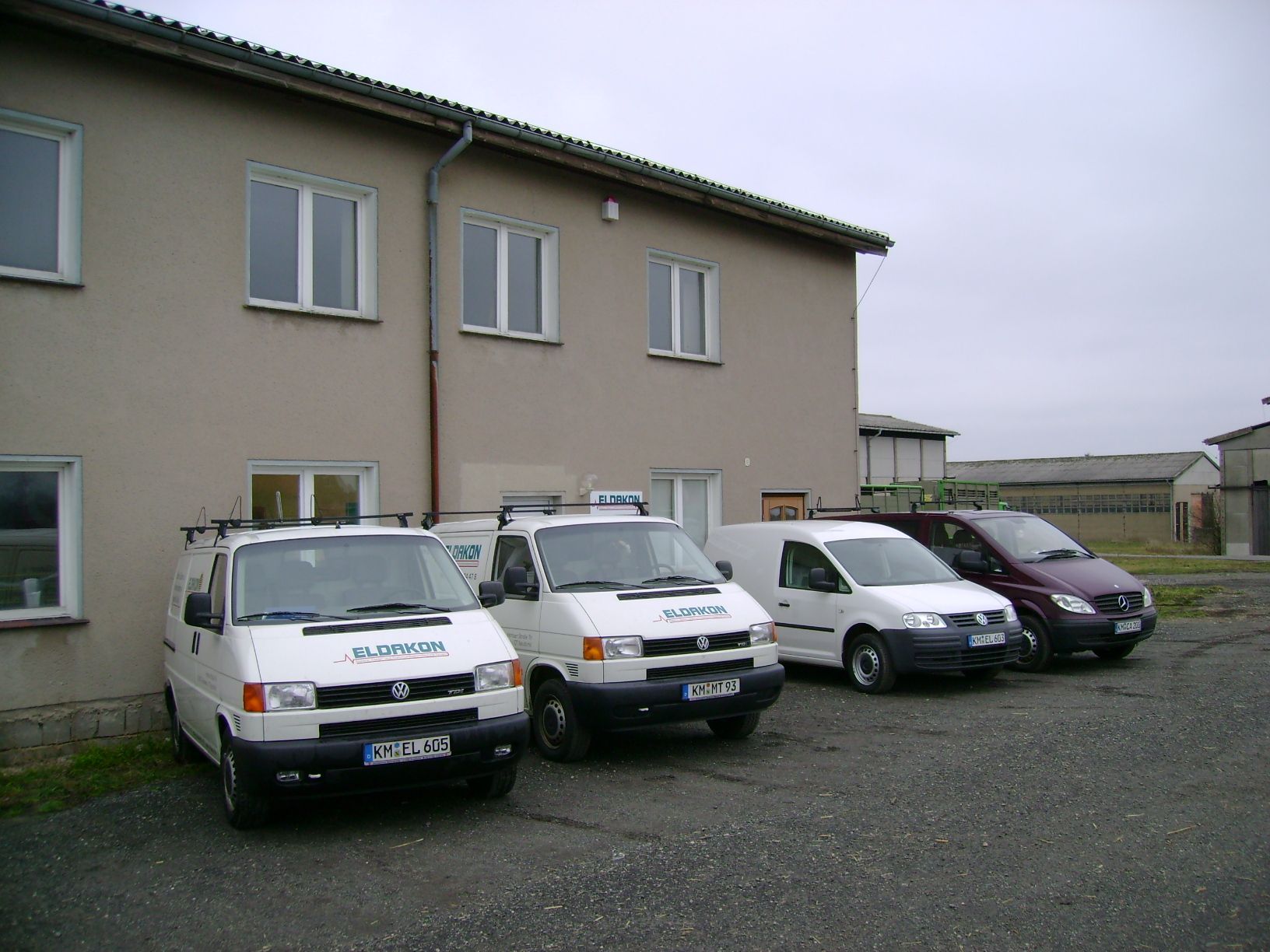 Firmenfuhrpark mit weißen Transportern vor dem zweistöckigen Firmensitz.