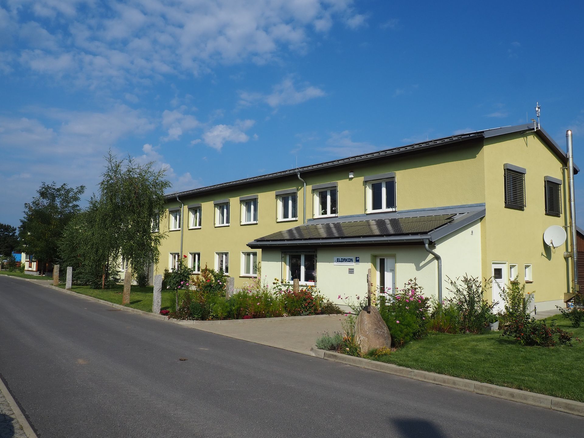 Ansicht des gelben Firmengebäudes mit zwei Etagen unter blauem Sommerhimmel.