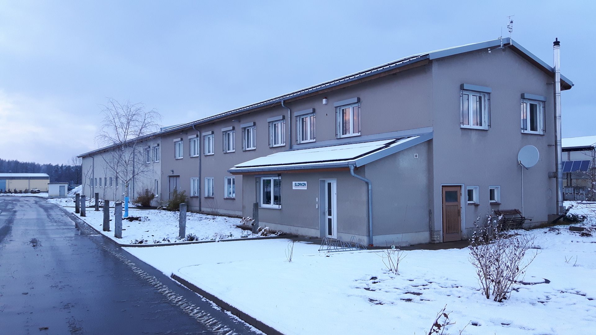 Langes, zweistöckiges Firmengebäude in einer verschneiten Winterlandschaft.