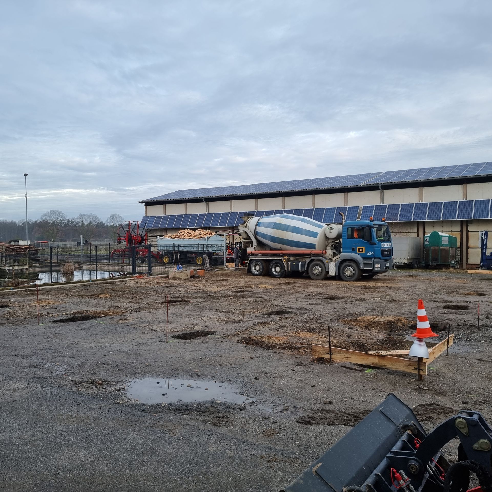 Betonmischer bei Bauarbeiten vor einem landwirtschaftlichen Betriebsgebäude.