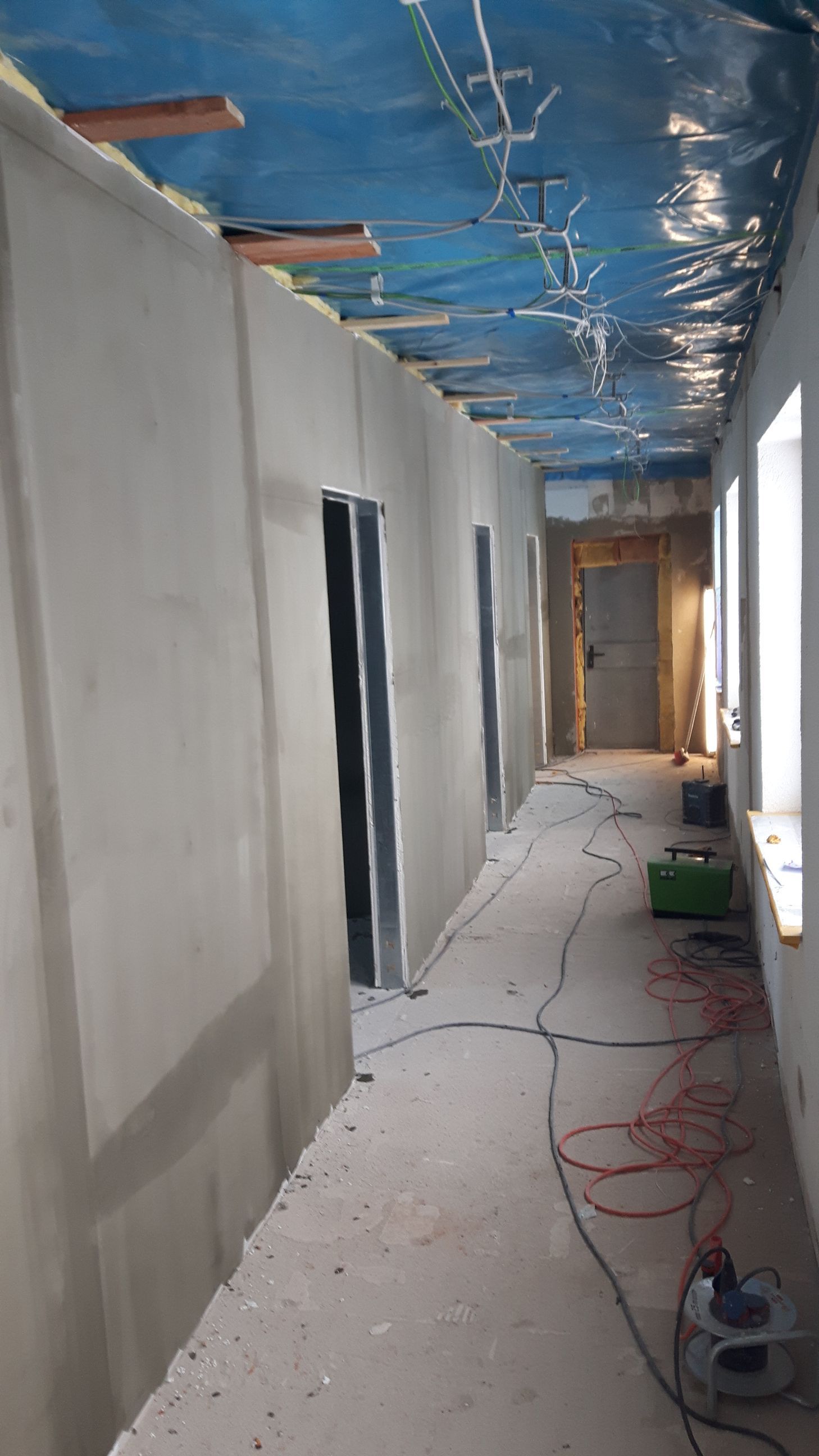 Detailansicht der Deckenverkabelung unter blauer Folie mit Holzträgern.