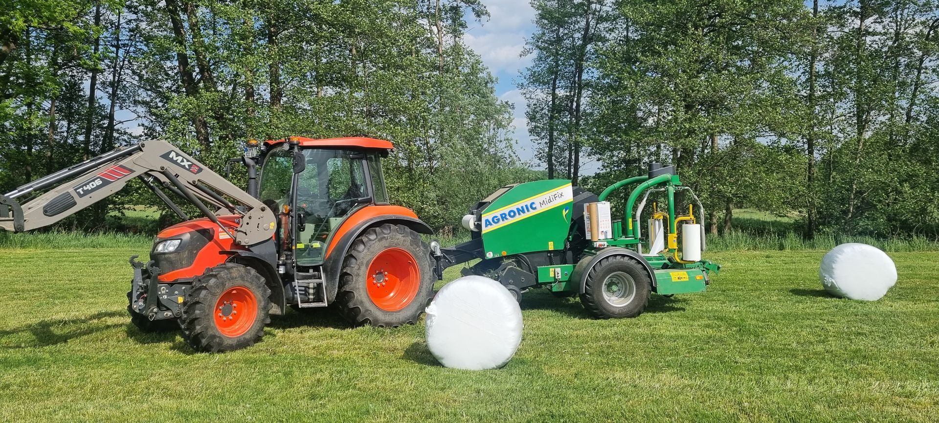 Traktor mit einer Agronic Press-Wickelkombination auf einer grünen Wiese.