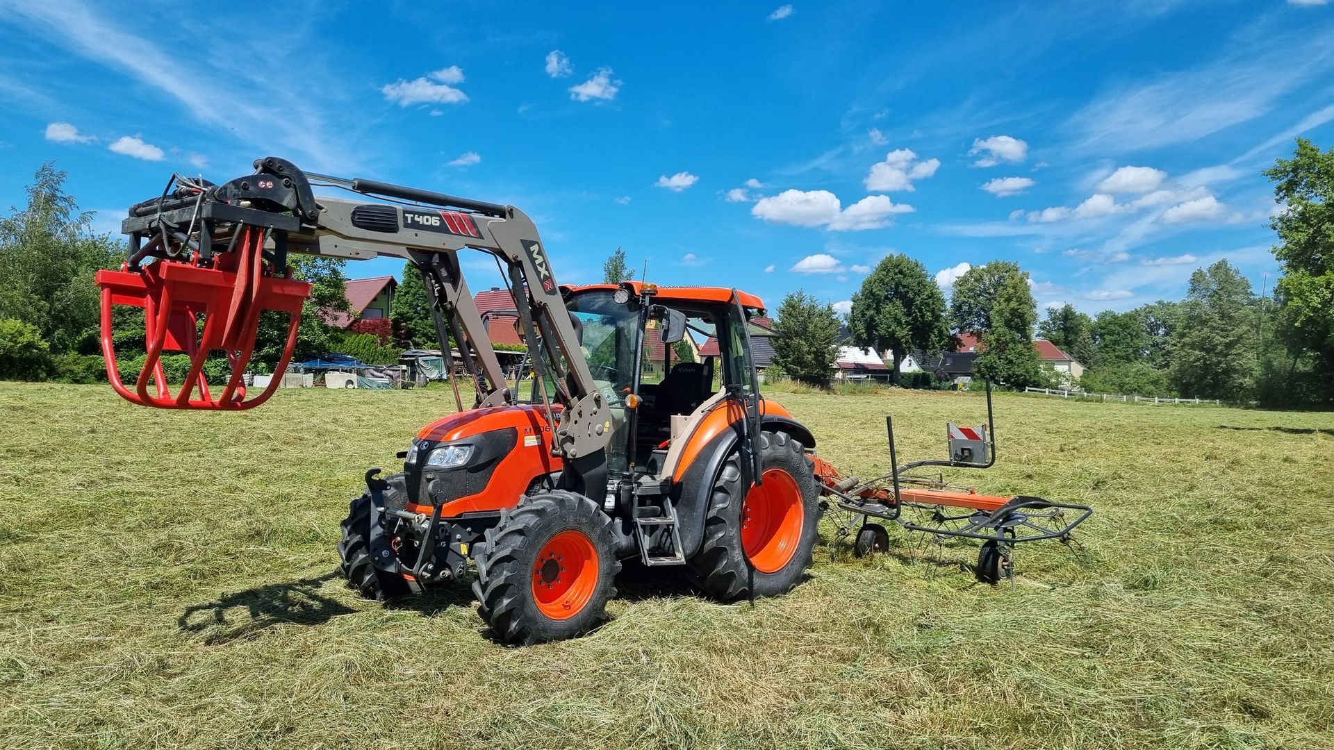 Moderner Traktor mit Frontlader und Heuwender im Einsatz auf dem Feld.