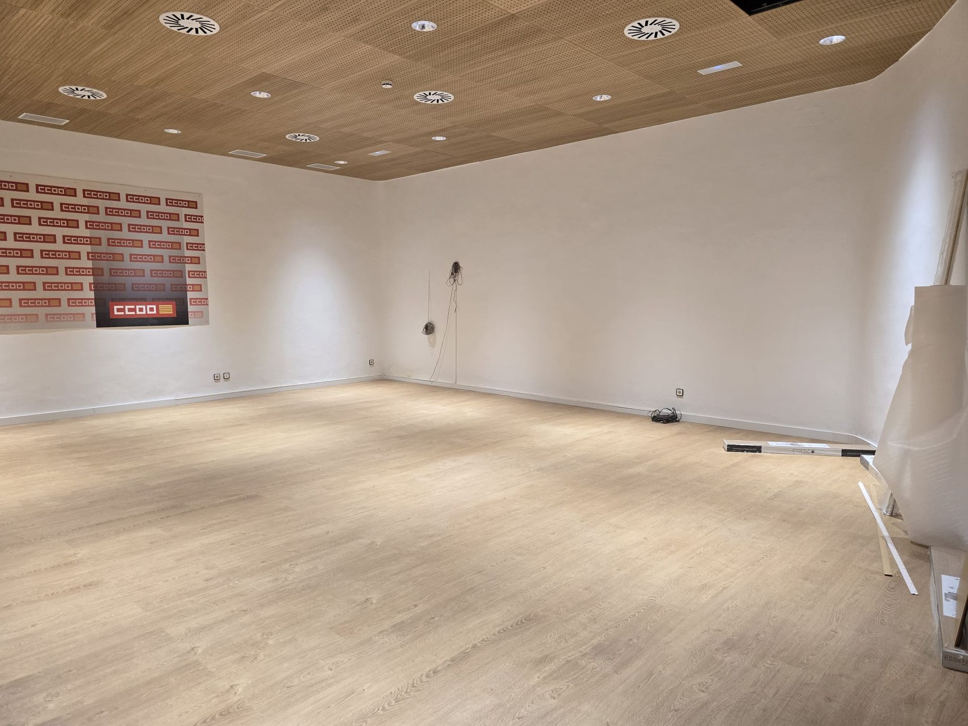 Alfombra beige estampada sobre un suelo de madera clara, frente a una pared lisa.