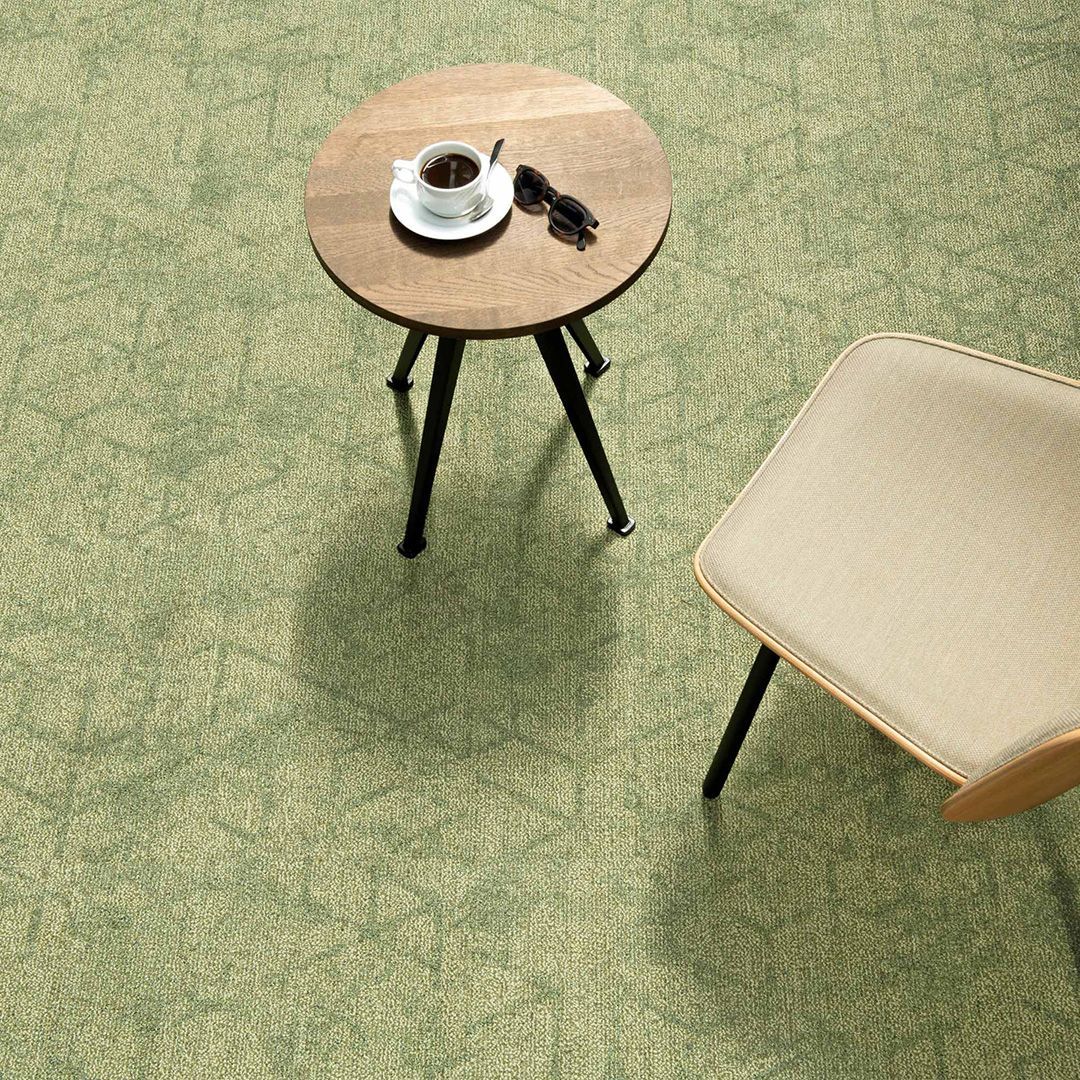 Elegante pasillo de hotel con alfombra de estampado rojo y dorado, lámparas de araña y paneles de madera oscura.