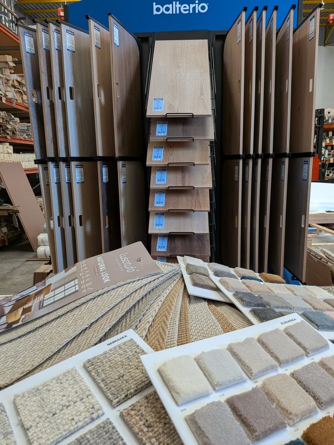 Alfombra texturizada de tonos neutros beige, gris y azul colocada en el suelo de un interior.