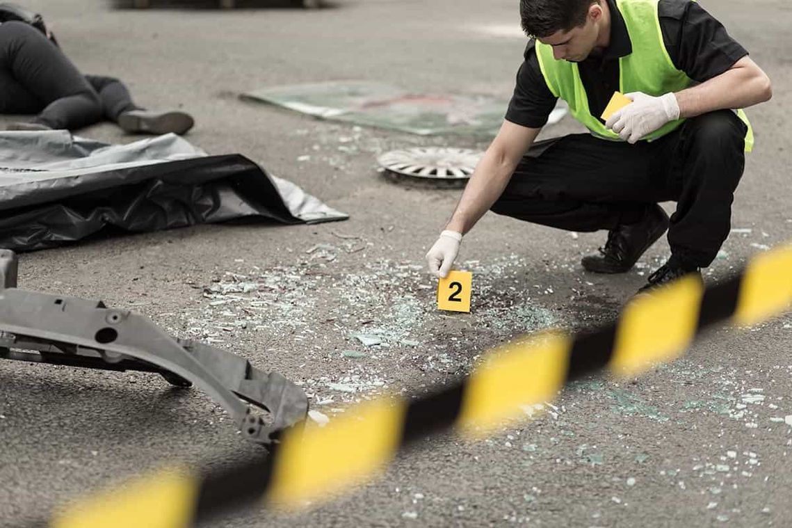 Un hombre está arrodillado en la escena de un accidente automovilístico.