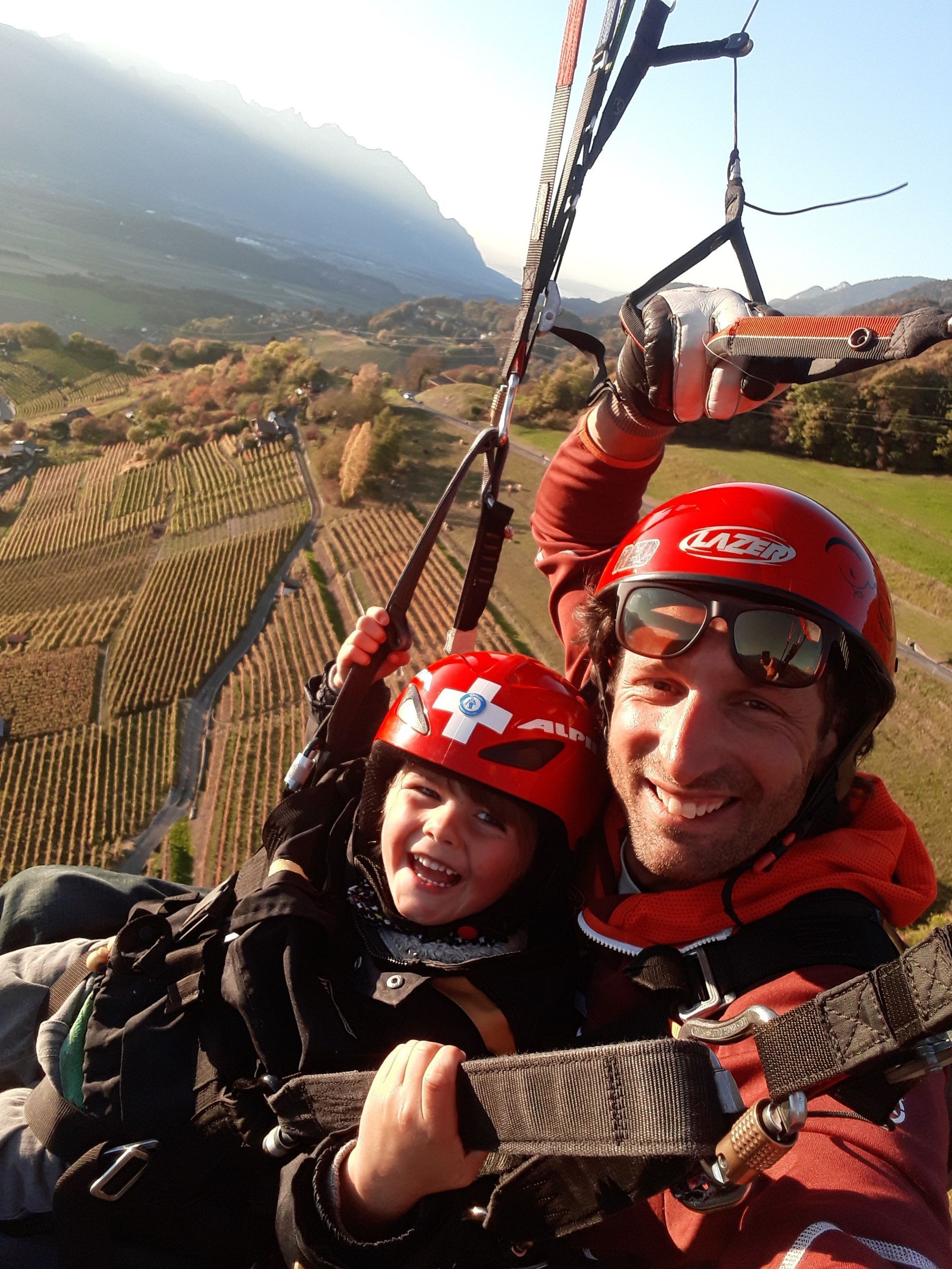 Un homme et un enfant portant des casques rouges pilotent un parachute