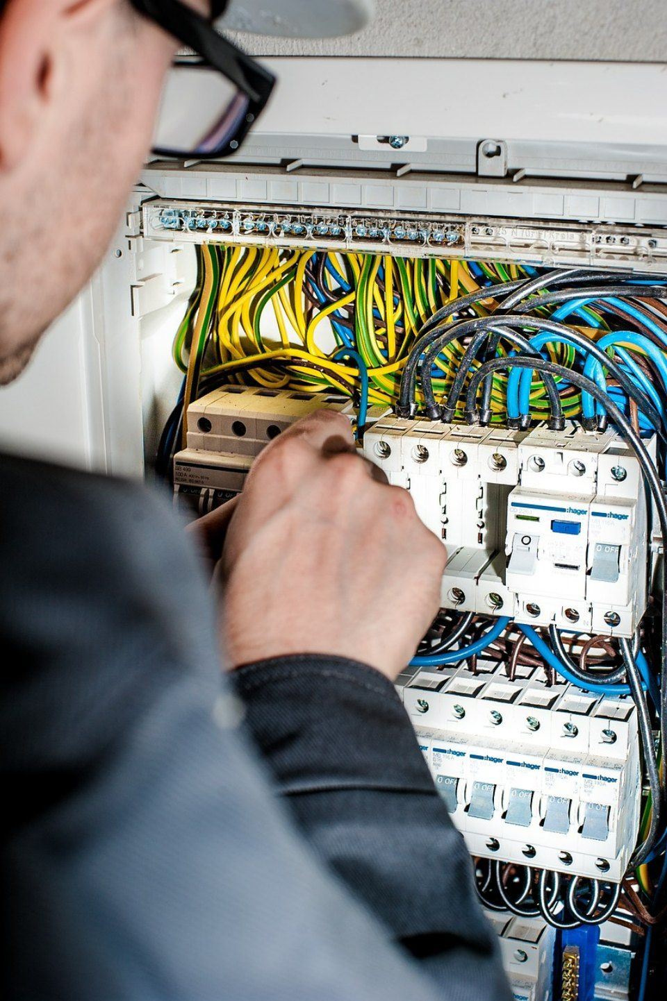 Ein Mitarbeiter der Elektrotechnik Fix GmbH prüft die Kabel in einem Stromkasten