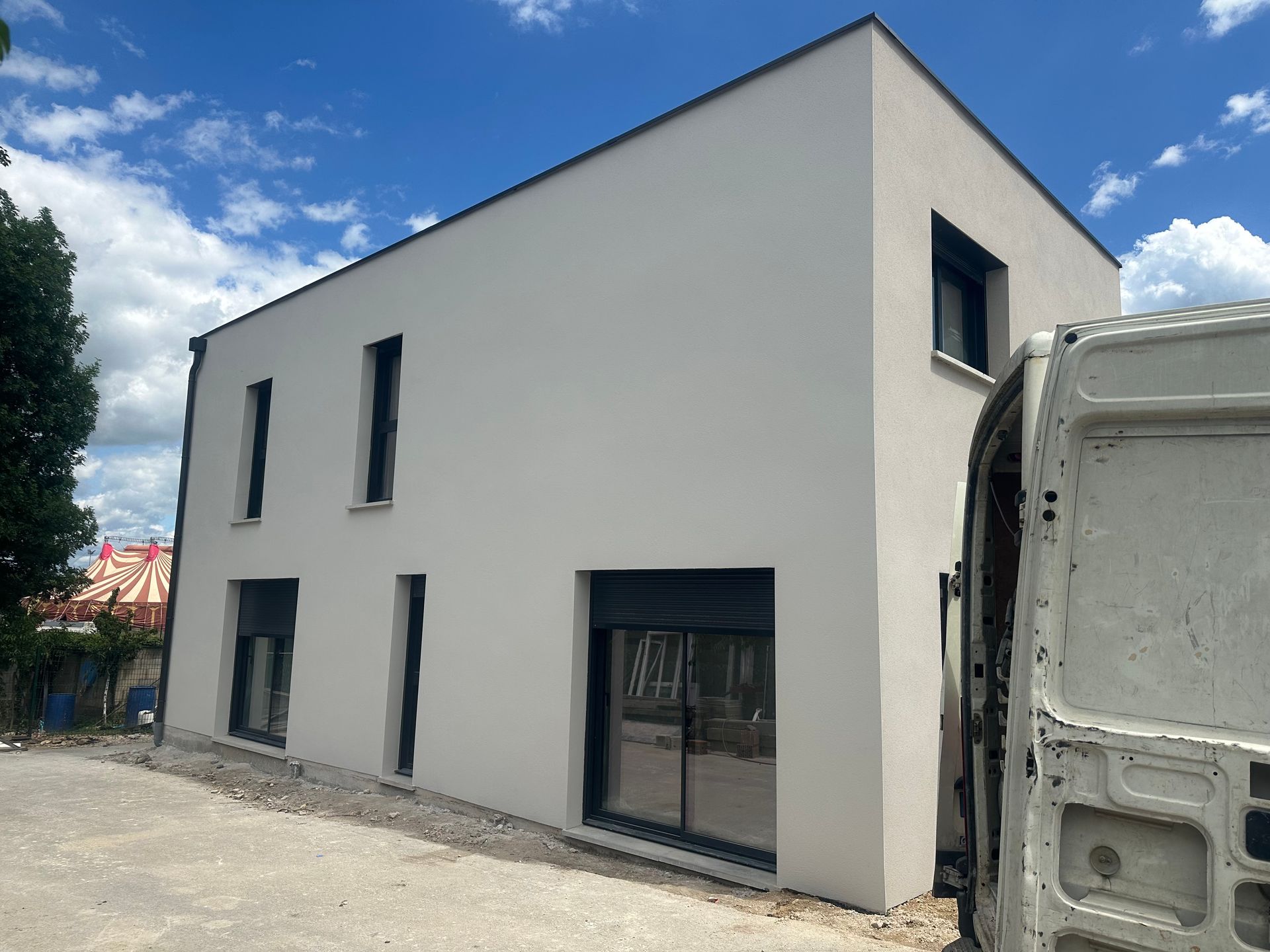 Extérieur d’une maison en construction, avec des échafaudages et des panneaux de façade blancs