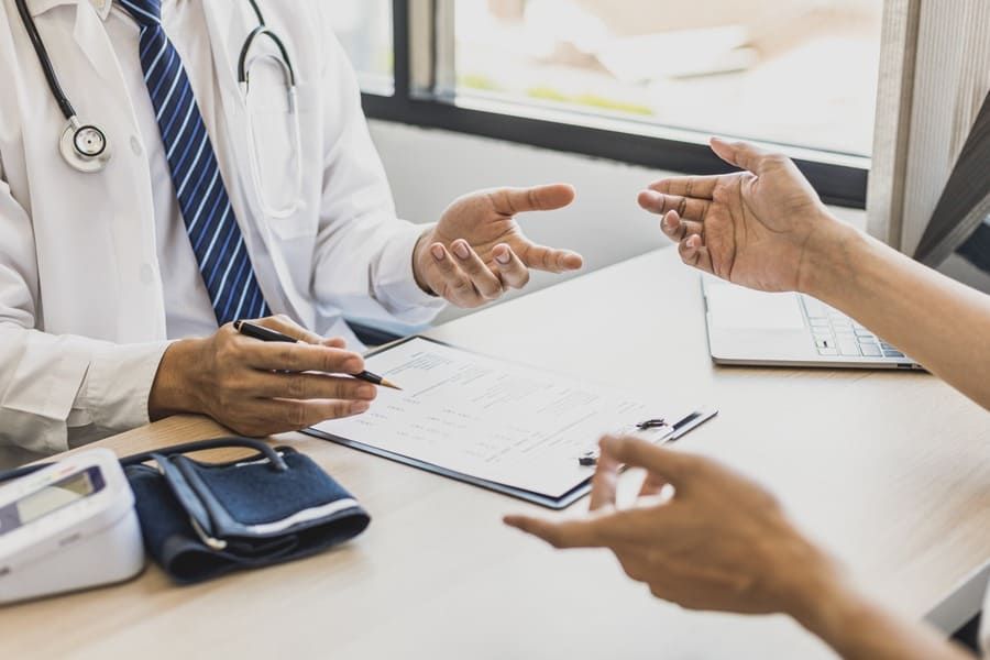 Un médico está hablando con un paciente mientras está sentado en un escritorio.