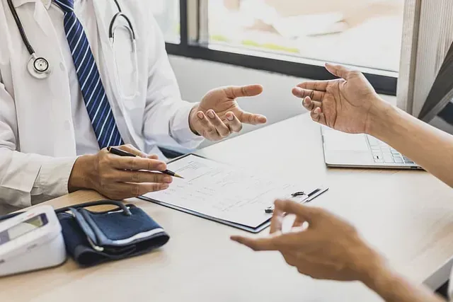 Un médico está hablando con un paciente mientras está sentado en un escritorio.