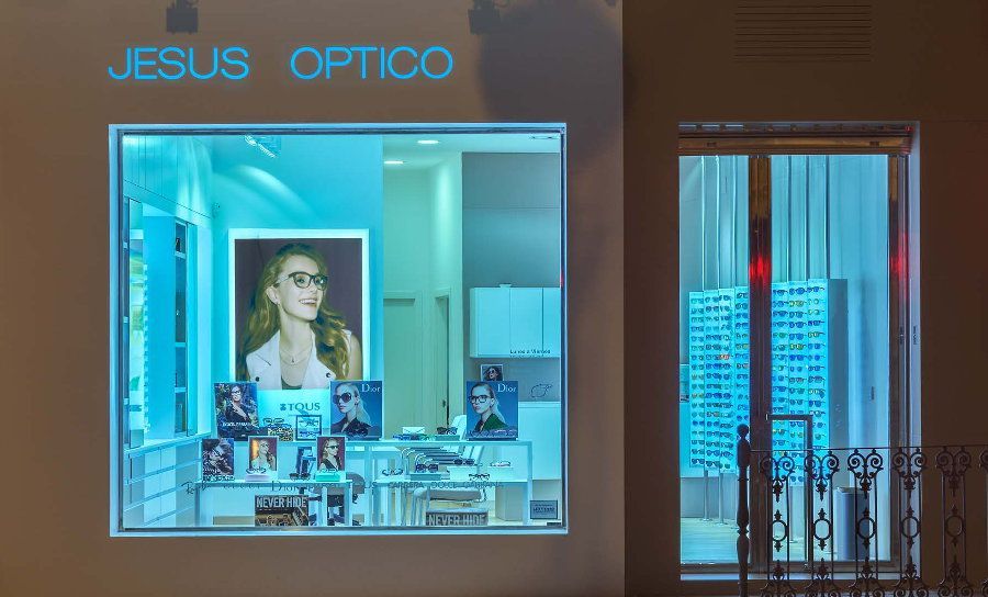 Escaparate nocturno de una óptica con escaparate que muestra unas gafas y una fotografía de una mujer usándolas.