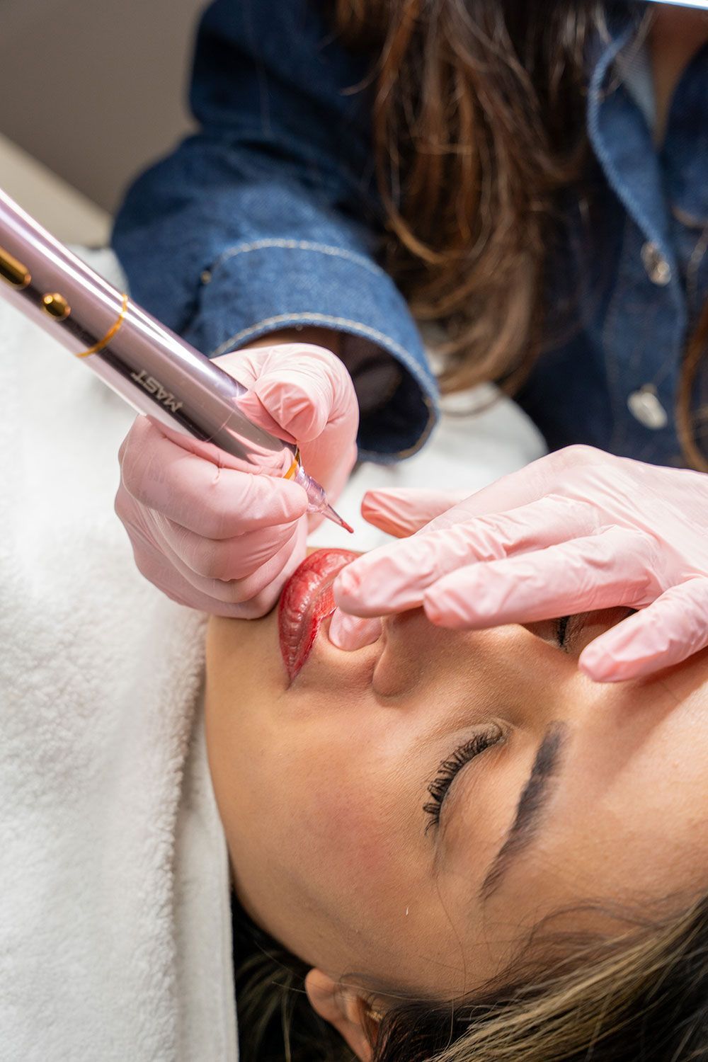 Eine Frau lässt sich ein permanentes Lippentattoo auf die Lippen stechen.