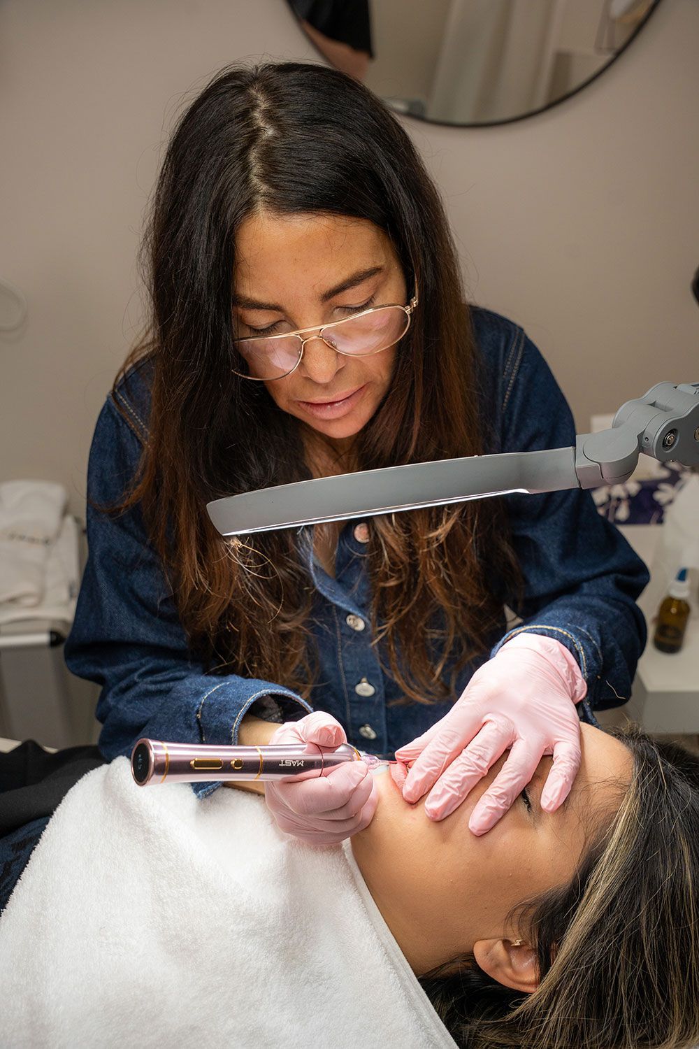 Eine Frau bringt ein Tattoo auf dem Gesicht einer anderen Frau an.