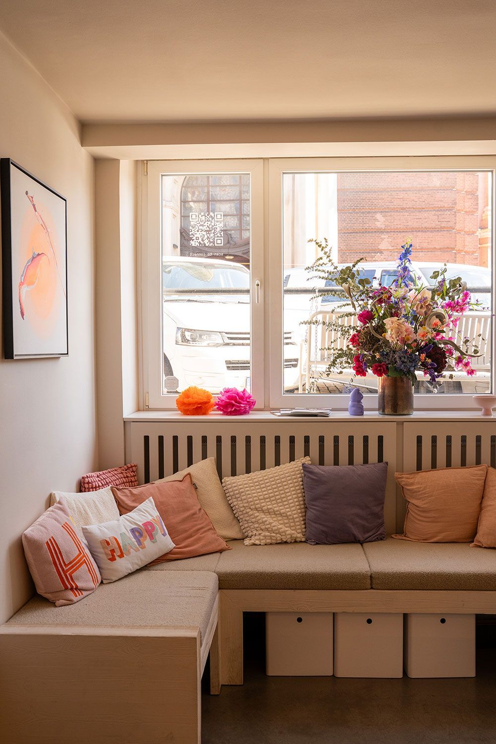 Ein Wohnzimmer mit einem Sofa und einer Blumenvase auf der Fensterbank.