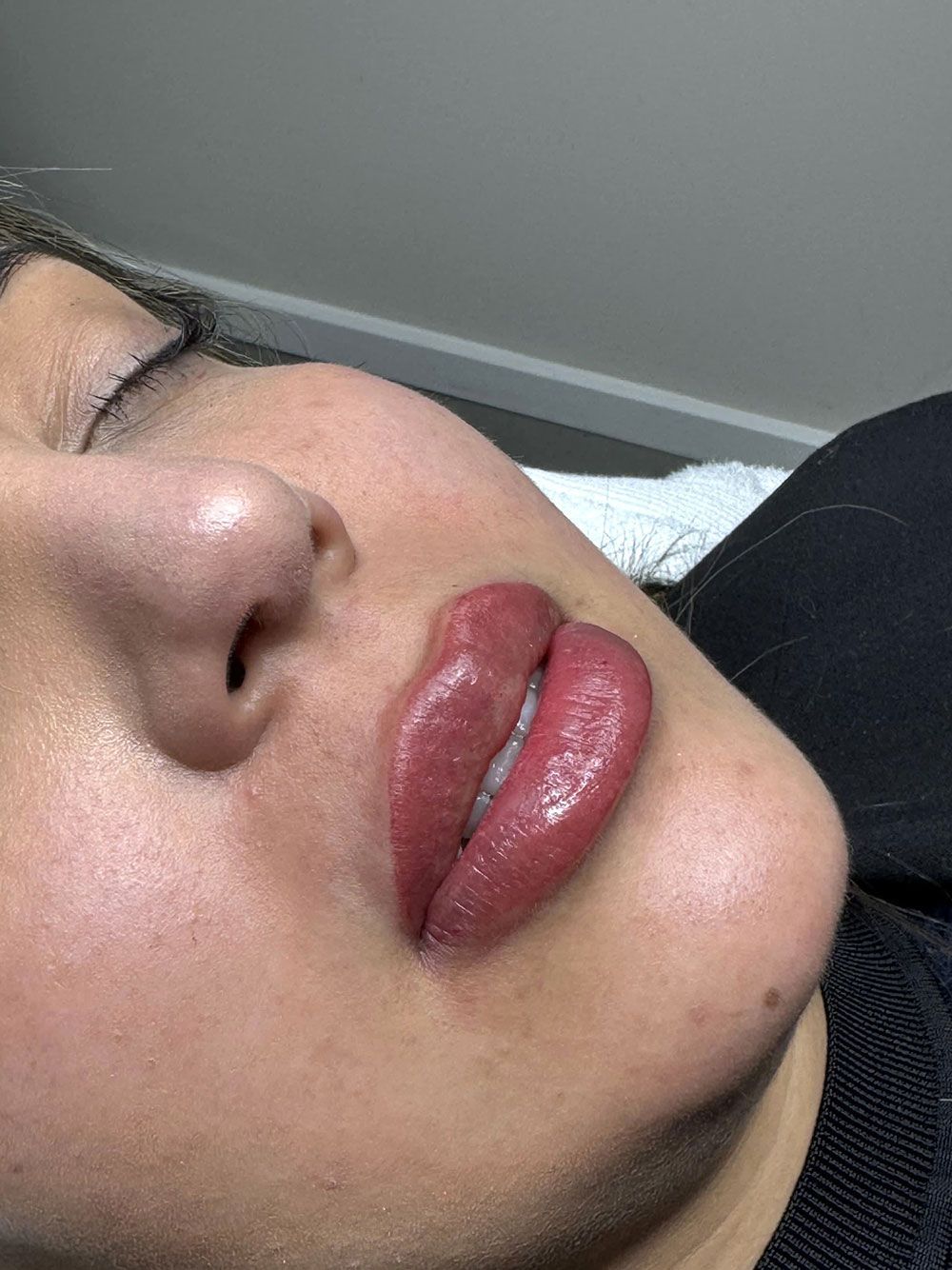 Eine Frau mit roten Lippen liegt mit geschlossenen Augen da.