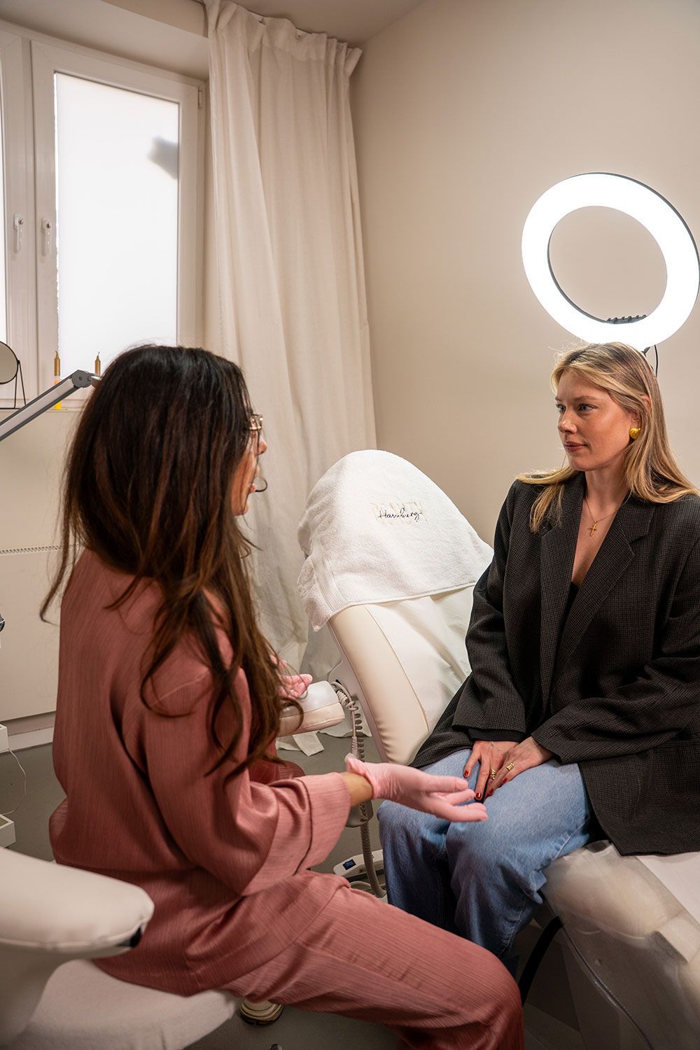 Eine Frau sitzt auf einem Stuhl und unterhält sich mit einer anderen Frau in einem Raum.