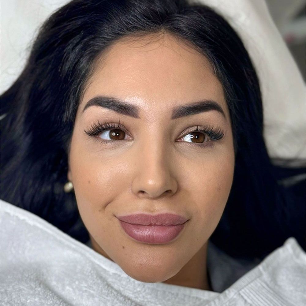 Eine Nahaufnahme des Gesichts einer Frau mit langen schwarzen Haaren und rosa Lippen.