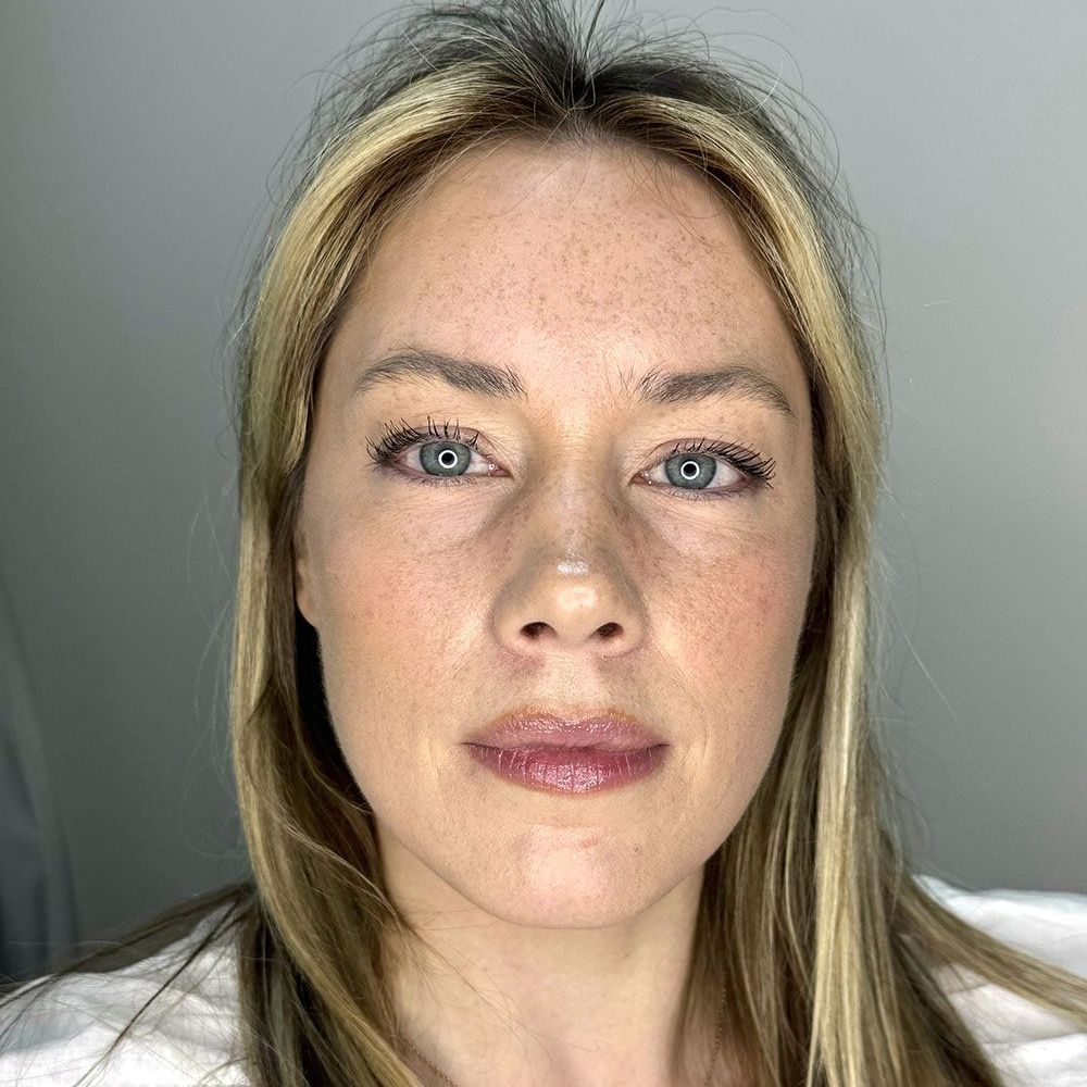 Eine Nahaufnahme des Gesichts einer Frau mit langen blonden Haaren und blauen Augen.