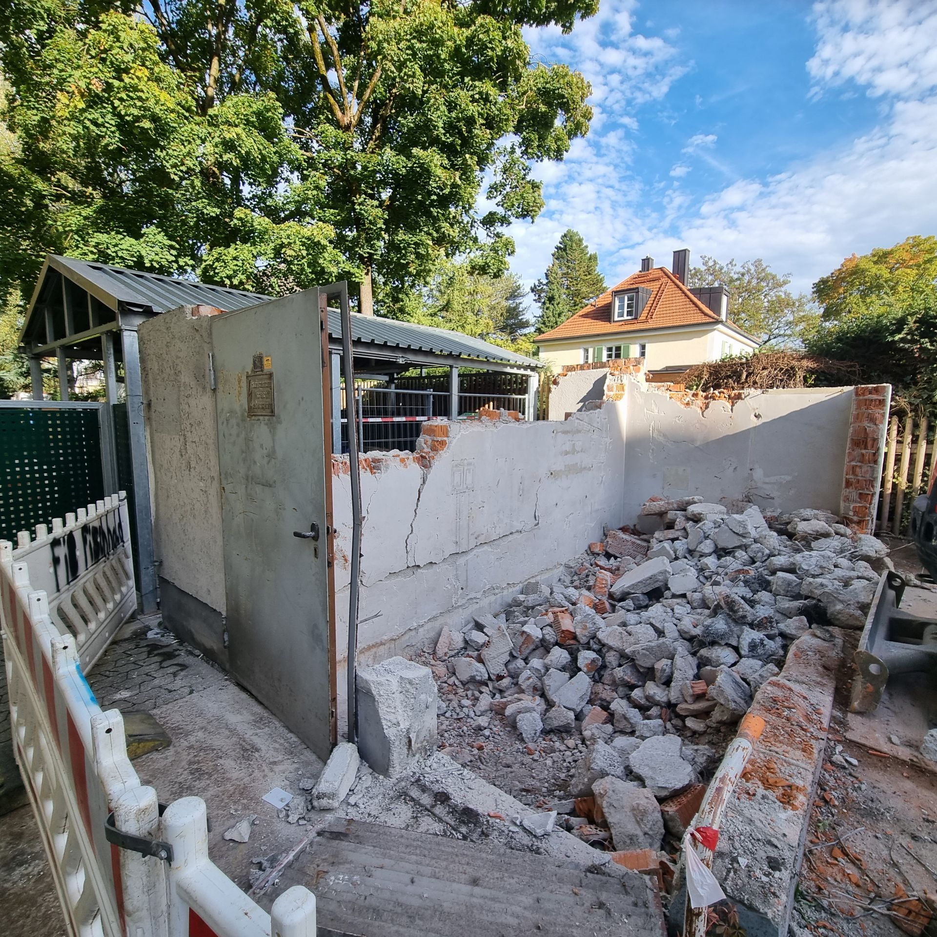 Abgerissene Ziegel- und Betonkonstruktion mit einem Schutthaufen davor, blauer Himmel darüber.
