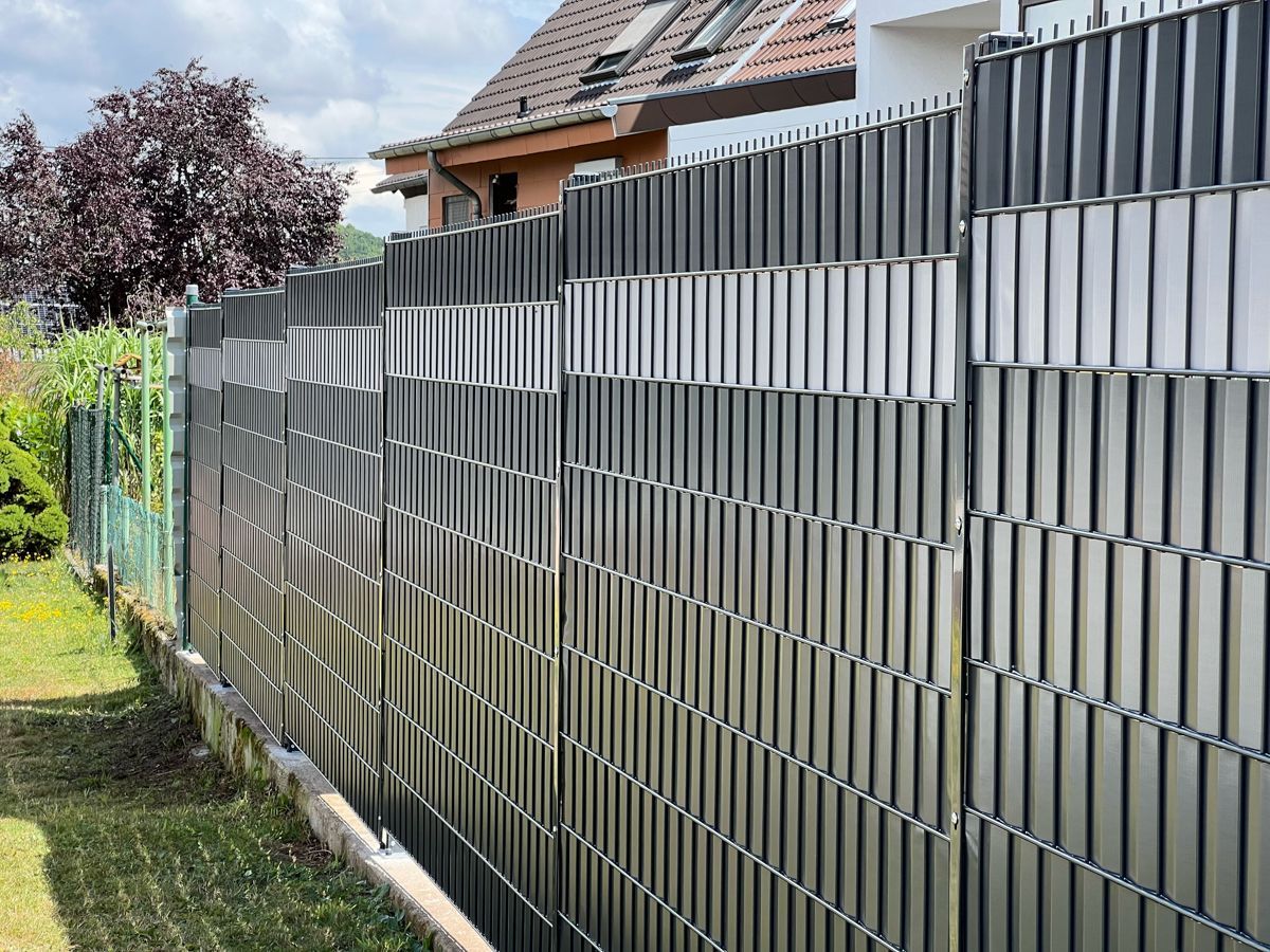 Grau-weißer Sichtschutzzaun in einem Hinterhof.