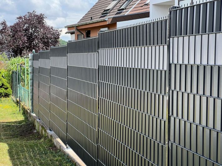 Grau-weißer Sichtschutzzaun in einem Hinterhof.