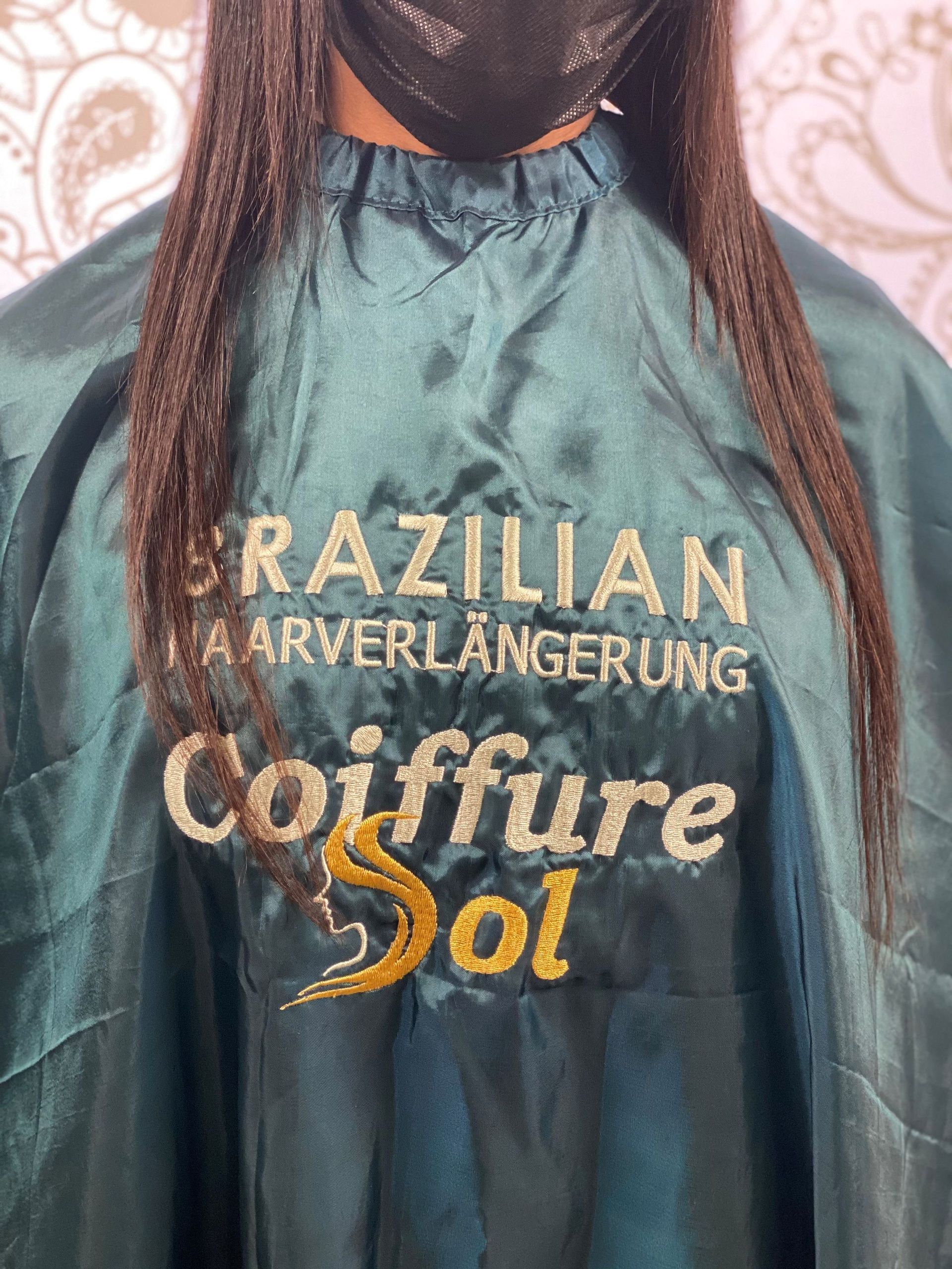 Salonumhang mit den in Gold gestickten Aufschriften „Brazilian Haarverlängerung“ und „Coiffure Sol“.