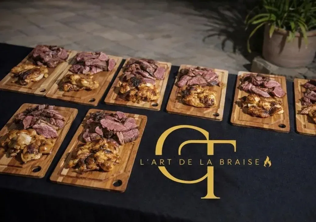 Planches de viande sur une nappe noire avec logo doré lors d'un événement en plein air.