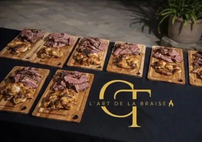Huit planches de viande placées sur une nappe noire ornée d'un logo doré, à l'extérieur, à côté d'une plante en pot.