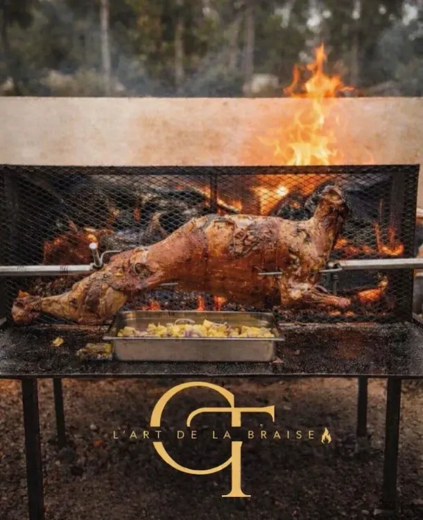 Cochon entier rôti à la broche au-dessus d'un feu de bois sur un barbecue extérieur.