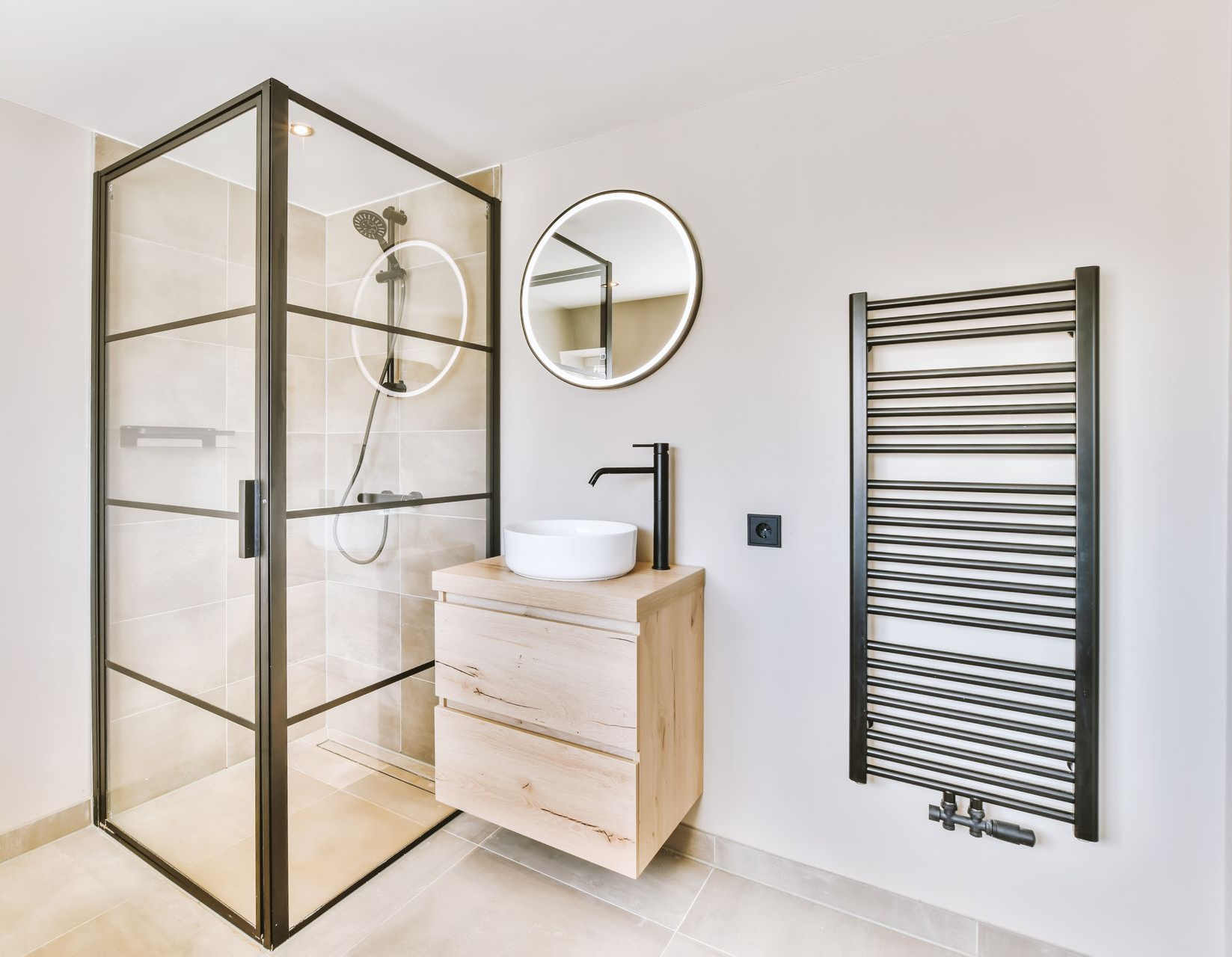 Une salle de bains avec une douche, un lavabo, un miroir et un sèche-serviette.