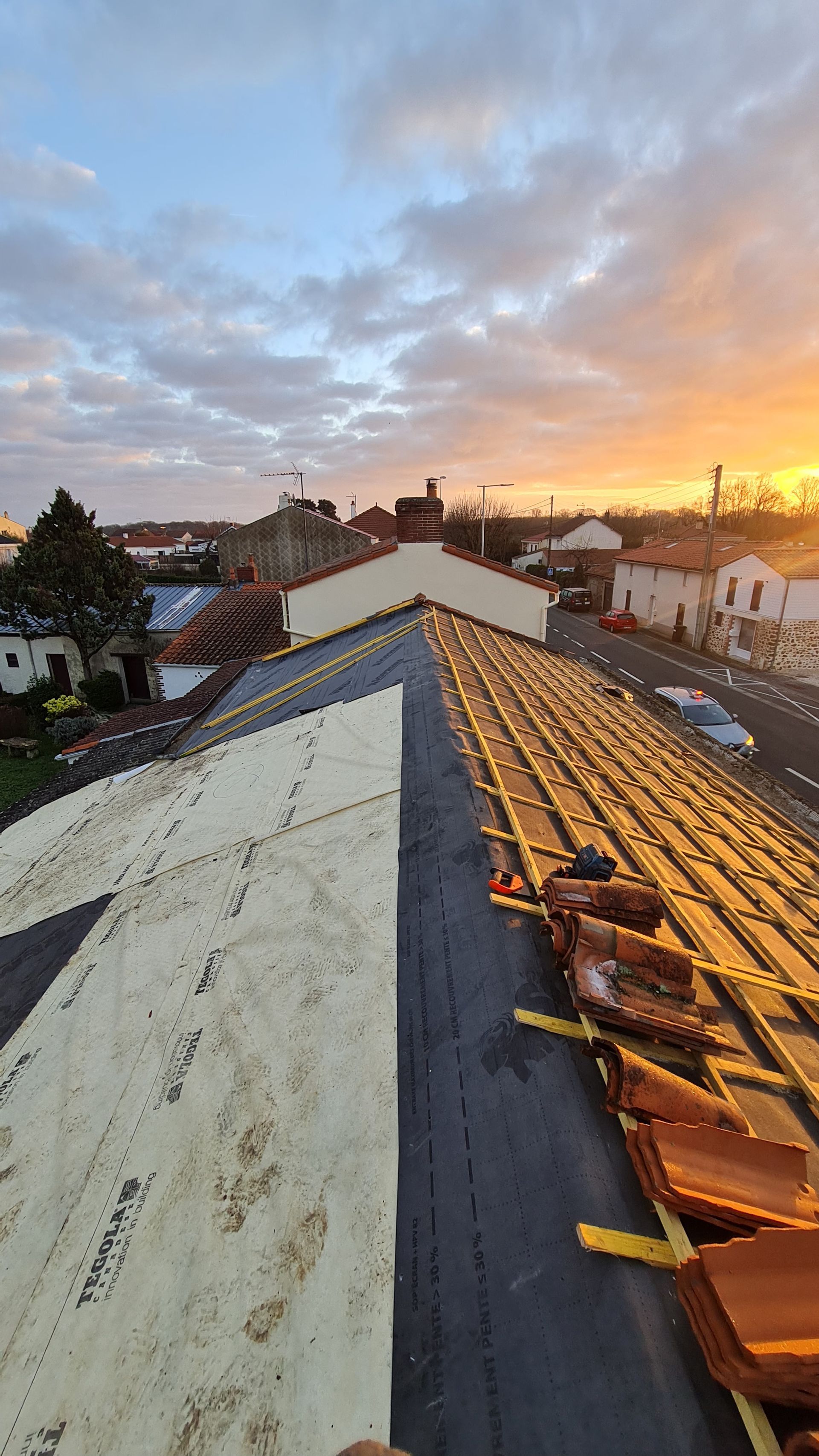 Photo de la rénovation d'une toiture prise lors d'un couché de soleil