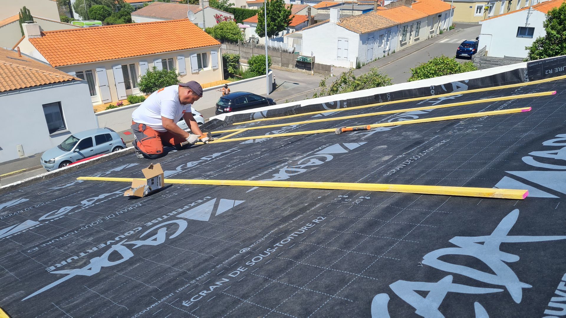 Photo d'un homme installant un feutre de sous toiture