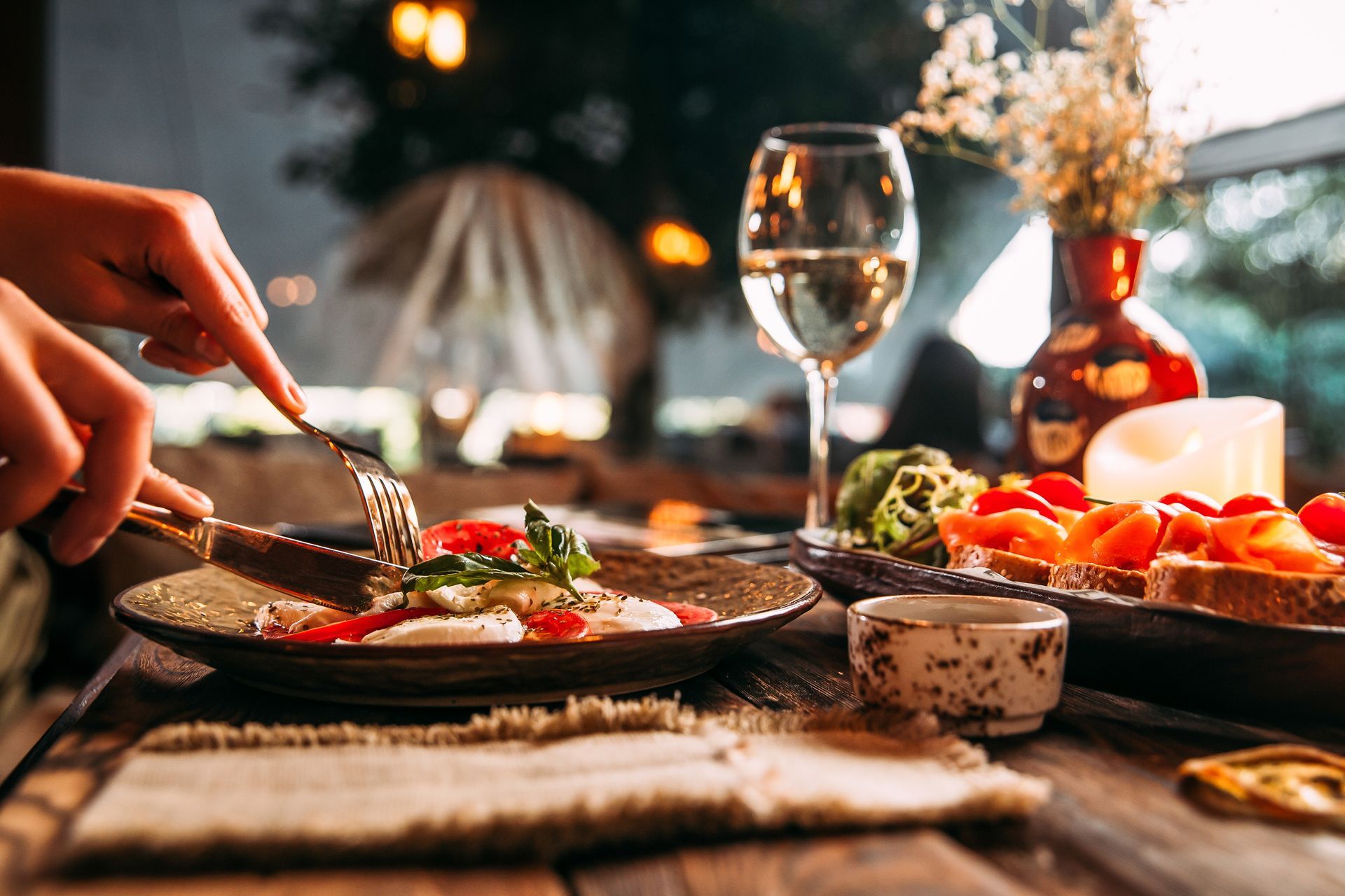 Eine Person isst einen Teller Essen an einem Tisch und trinkt ein Glas Wein.
