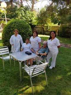 Un grupo de personas están de pie alrededor de una mesa y sillas en un parque.