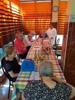 Un grupo de personas están de pie alrededor de una mesa y sillas en un parque.