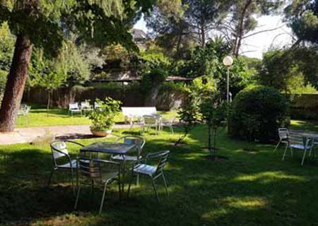 Un jardín con mesas y sillas en el medio.
