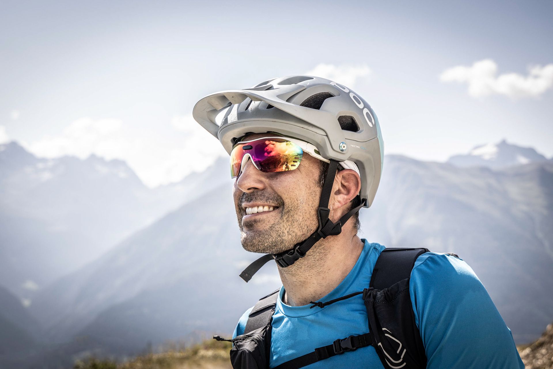 Ein Mann mit Helm und Sonnenbrille steht vor einem Berg.