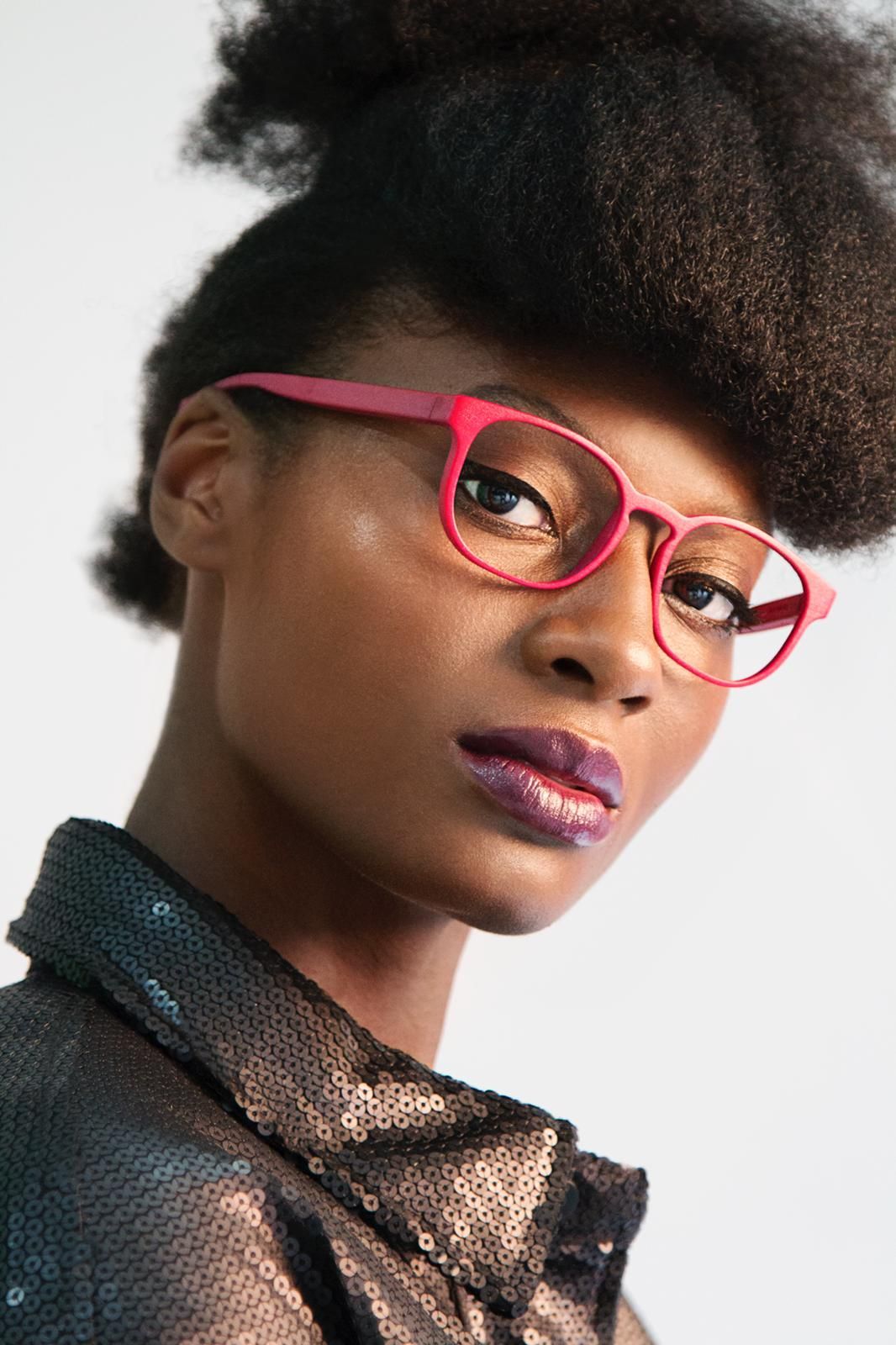 Eine Frau mit Brille und Paillettenhemd schaut in die Kamera.
