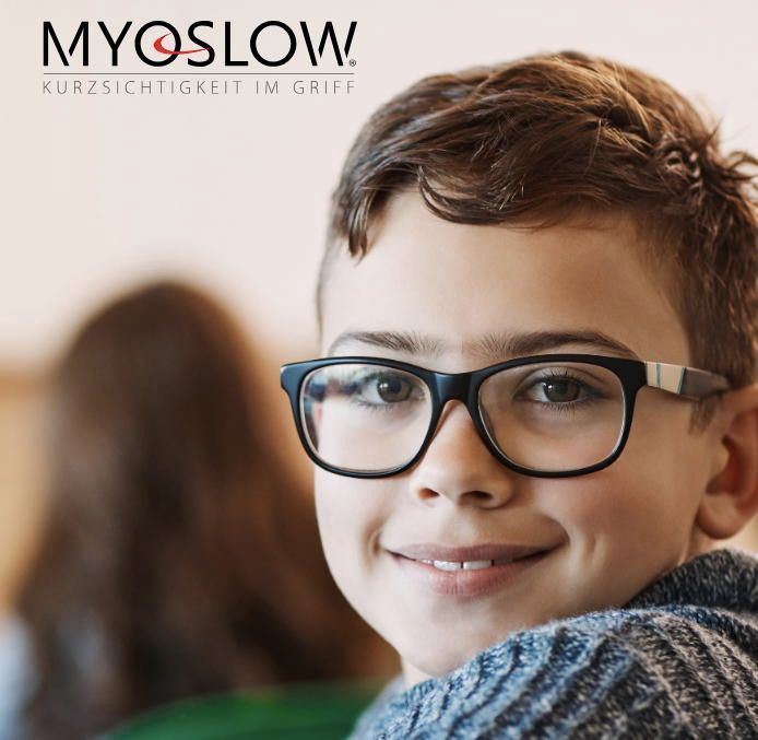 Ein kleiner Junge mit einer Brille, auf deren Unterseite Myoslow steht